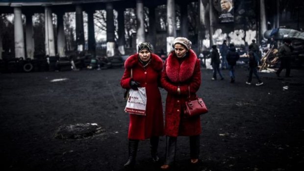 Women walk in front of a football stadium in KIev.