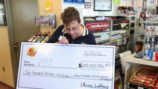Illinois Moto Mart store manager Denise Metzger looks at an oversized cheque given to her by lottery officials