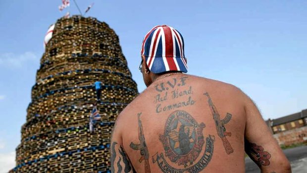 A Loyalist with paramilitary tattoos stands guard over a bonfire near the loyalist Shankill road in Belfast.