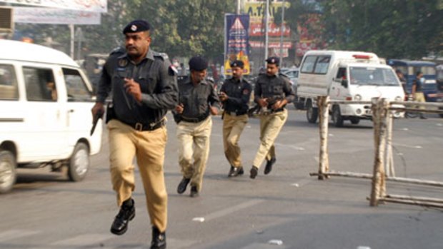 Police run to take up positions outside the Federal Investigation Agency in Lahore