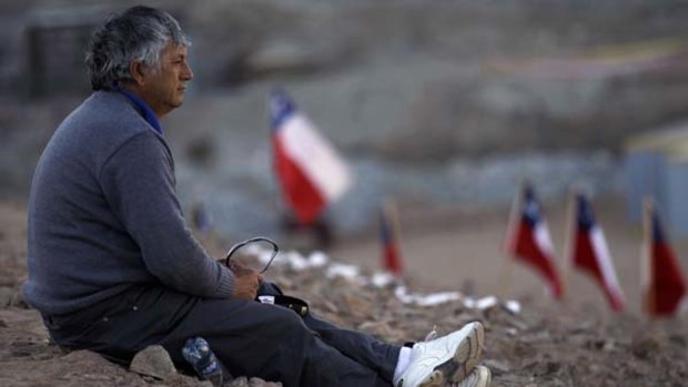 Oscar Illanes, brother of one of the trapped miners, sits outside the collapsed San Jose mine.