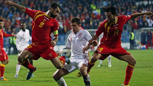 England's Michael Carrick (C) is tackled by Montenegro's Mirko Vucinic (L) and Dejan Damjanovic.