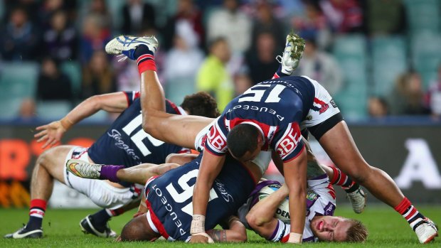Crunched: Storm fullback Cameron Munster is pummelled by Roosters duo Kane Evans and Sio Siua Taukeiaho at Allianz Stadium.
