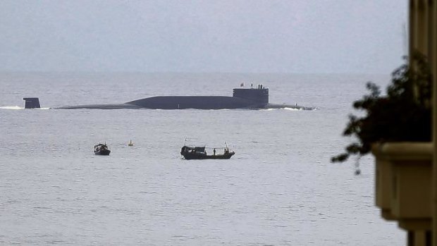 Fishermen look at a Chinese nuclear submarine that sails past Yalong Bay in Sanya, south China's Hainan Province.