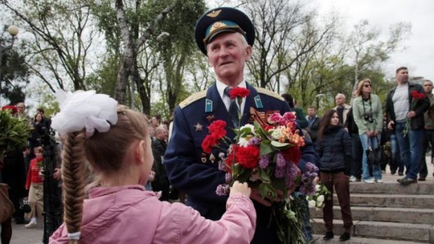 Honours: A girl gives flowers to a veteran at a monument to the Unknown Sailor during celebrations marking Victory Day in Odessa. WWII veterans salute at a war memorial during Victory Day celebrations.