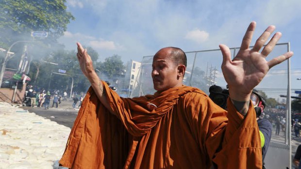 A Buddhist monk raises his hands in a bid to stop policemen firing tear gas in Bangkok on Sunday.