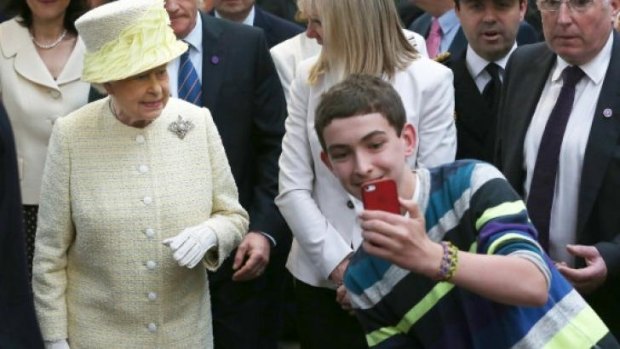 Culture clash: A young boy takes a selfie photograph in front of Queen Elizabeth II. 
