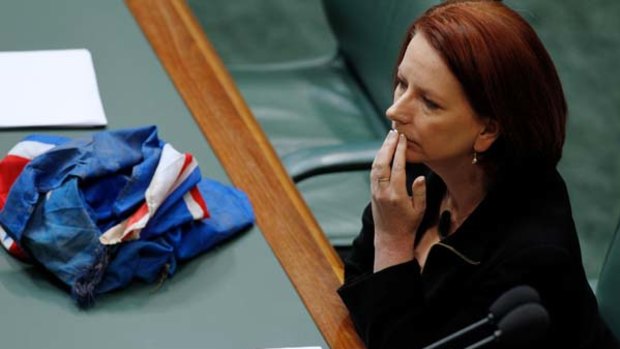 Misty moment ... Julia Gillard's feelings about the floods show in Parliament, the flag recovered from Murphy's Creek at her side.