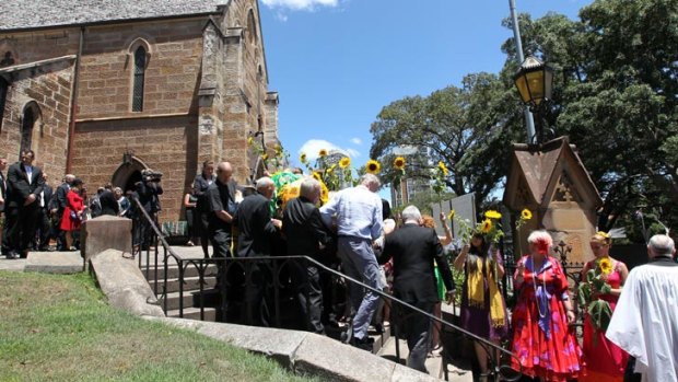 Former students held aloft bright sunflowers as Courtenay's casket left the church. <i>Photo: Janie Barrett.</i>