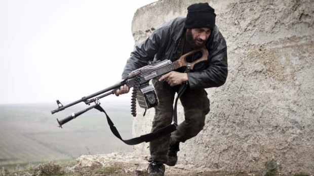 War within a war ... In this file photo, a Free Syrian Army fighter takes cover during fighting with the Syrian Army in Azaz, Syria. Al-Qaeda-linked gunmen in northern Syria captured a town near the Turkish border after clashing with Western-backed rebels on Thursday.