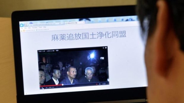 A man uses a laptop to browse a home page of the "Banish Drugs and Purify the Nation League" website displaying a video of Kenichi Shinoda, the boss of the Yamaguchi-gumi, Japan's largest yakuza.