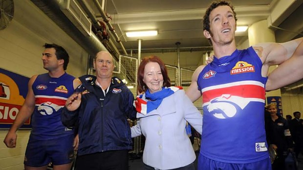 Julia Gillard joins (from left) Brian Lake, coach Rodney Eade and Robert Murphy in singing the song after the win over North Melbourne on August 1, 2010.