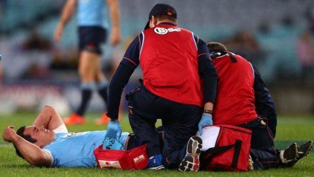 Down and out: Waratahs captain Dave Dennis has his injured knee treated during Saturday night's match against the Brumbies.