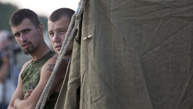 Two Ukrainian soldiers, who fled the conflict territory, stand at a tent camp near the village of Gukovo, southern Russia. A Russian border security official said Monday that more than 400 Ukrainian soldiers have crossed into Russia.