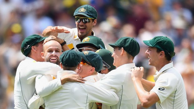 Nathan Lyon is mobbed by teammates after taking the wicket.