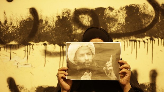 An anti-government protester in Bahrain holds a picture of Sheikh Nimr during clashes between police and protesters in Sanabis.