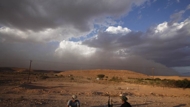 As the shadows lengthen and a sandstorm gathers, anti-Gaddafi fighters sit it out at Wadi Dinar, a checkpoint near Bani Walid.