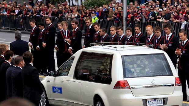 The Melbourne Football Club forms a guard of honour along Flinders Street as as Stynes' casket is driven from the cathedral.
