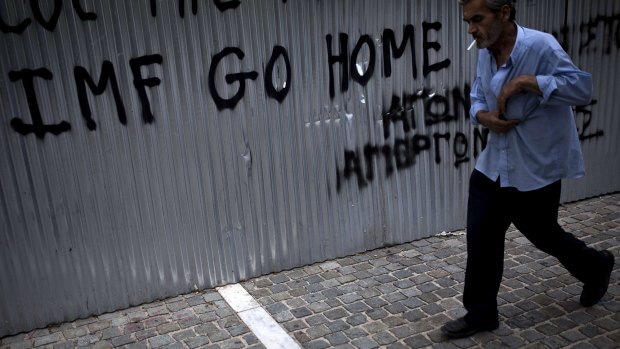 A man walks in front of a graffiti reading 'IMF go home' in Athens on Saturday. 