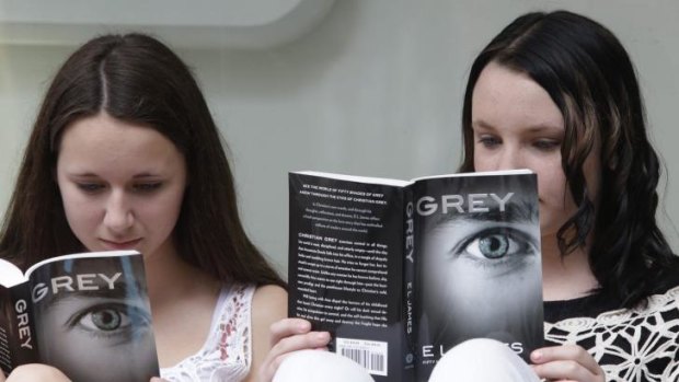 Fans of author EL James Olivia Jackson, 15, left, and Julia Cebula, 14, of Philadelphia, read as they line up outside a Barnes and Noble bookstore in New York to get an autograph from the author.