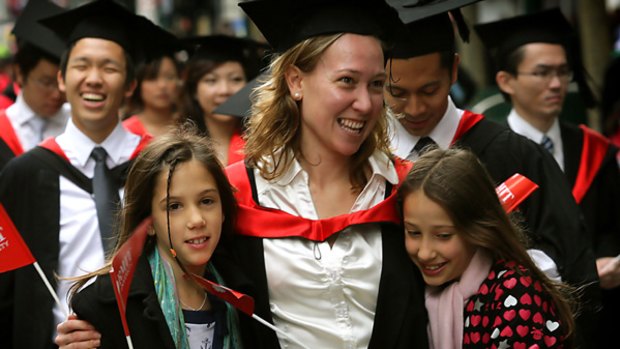 RMIT graduate Marie-Claire DeRozario is congratulated by her nieces Isabella and Evie Romic during the parade of 2000 graduates down Swanston Street to Federation Square yesterday.