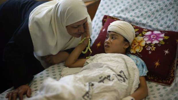 Nine-year-old Palestinian girl Maryam Al-Masri, who hospital officials said was wounded in an Israeli air strike, listens to her grandmother as she lies on a bed while receiving treatment at a hospital in Gaza City.