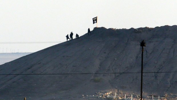 The black flag of Islamic State flies over the town of Kobane in Syria in October 2014.