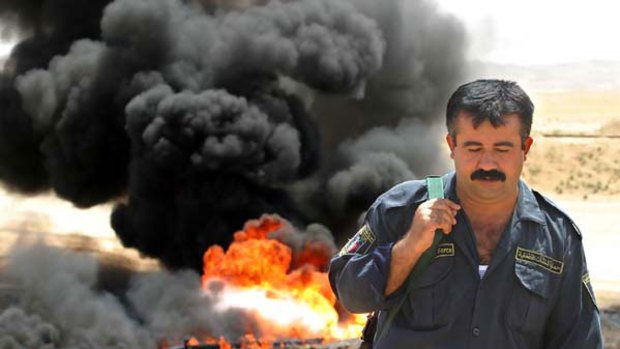 An Iraqi oil policeman investigates the sabotage of a pipeline near Kirkuk in 2006.