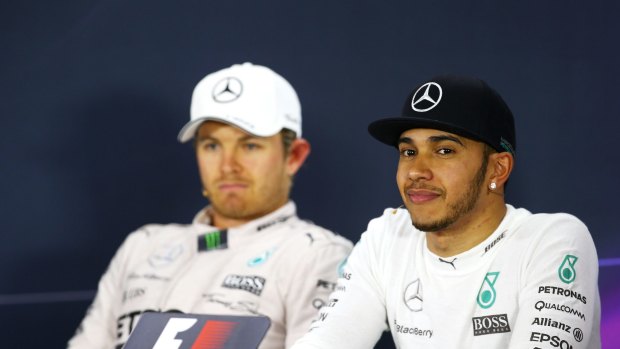Winners are grinners: Lewis Hamilton at the post-race media conference as Nico Rosberg watches on.
