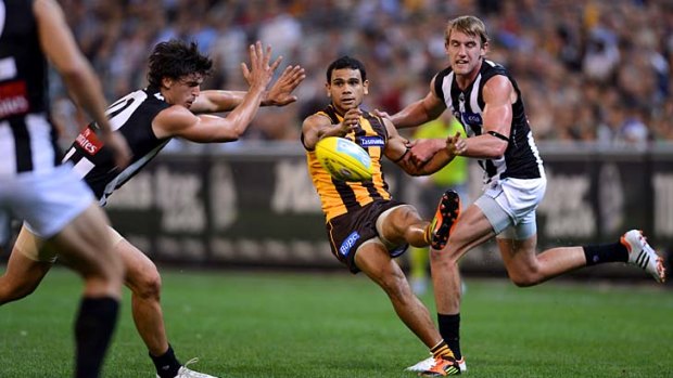 Cyril Rioli gets a kick away despite pressure from Collingwood players.