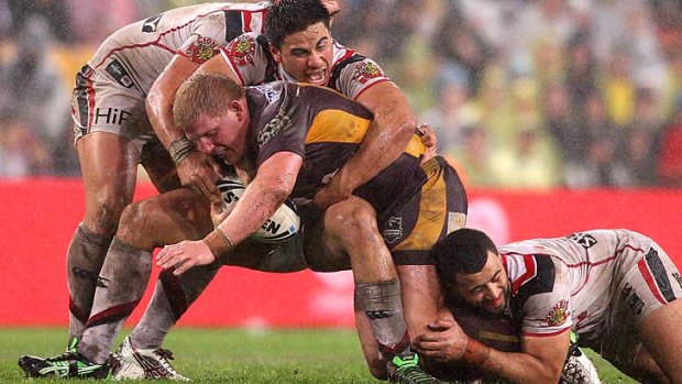 Ben Hannant takes on the Warriors defence on a slippery Suncorp surface.