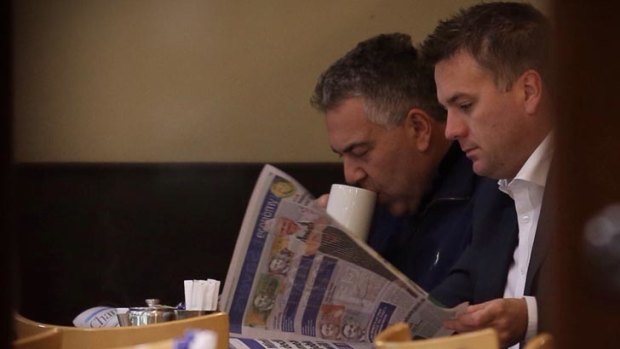 Treasurer Joe Hockey reads budget coverage with Assistant Minister for Infrastructure Jamie Briggs.