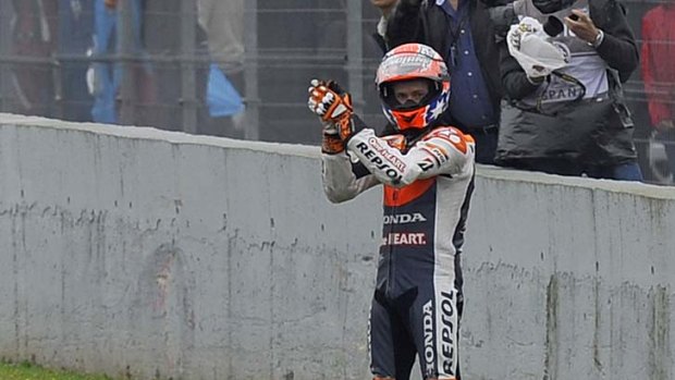 Casey Stoner gestures as Valentino Rossi rides away after their crash.