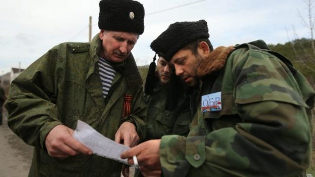 A Cossack commander (left) talks with two Serbian Chetnik militia men at a checkpoint heading towards Sevastopol from Simferopol.