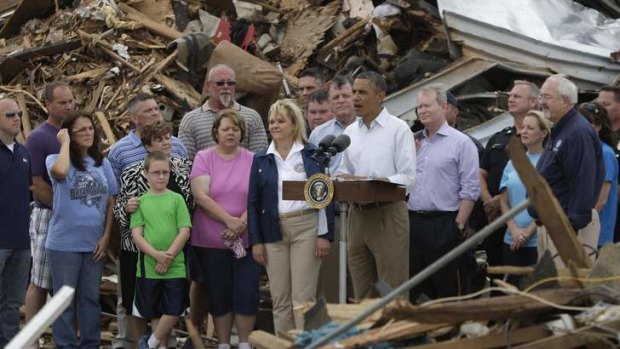 Sharing the pain: Barack Obama stands with survivors and first responders as he speaks to reporters amidst the rubble of the tornado-destroyed Plaza Towers Elementary School in Moore, Oklahoma on Sunday.