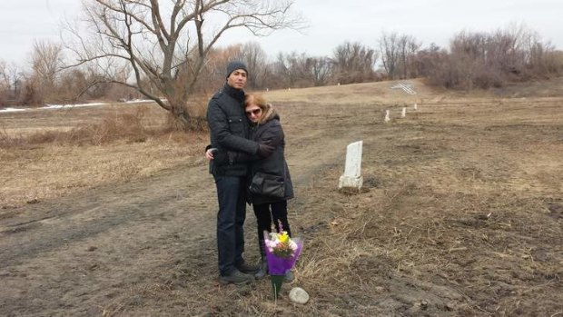 Elaine Joseph with her son on Hart Isalnd. Each white post marks 150 adults or 1000 babies buried.