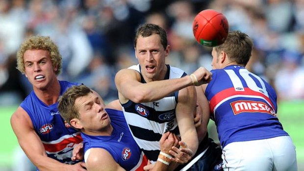 Surrounded by three Dogs ... Geelong's James Kelly handballs out of pressure during the Cats' commanding win yesterday.