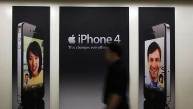 A customer walks past an iPhone 4 advertisement at a store in Melbourne.