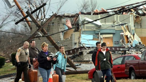 Blown apart ... a police officer helps evacuate residents from their wrecked home in Missouri. Tornadoes have killed six people.