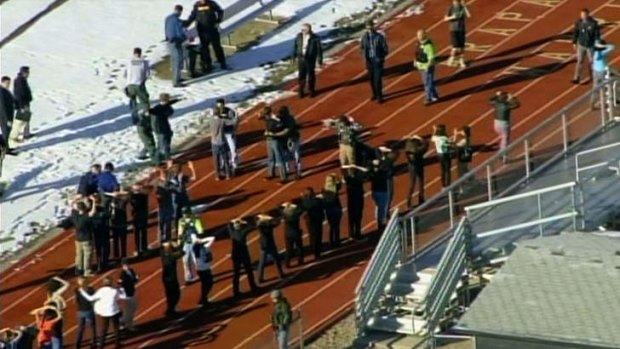 Students of Arapahoe High School in Centennial, Colorado, line up to be checked by police at a running track after a shooting at the school.