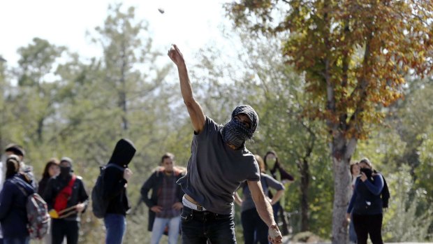 A demonstrator throws a stone at anti-riot police during clashed outside of the Middle Eastern Technical University (METU) in Ankara.