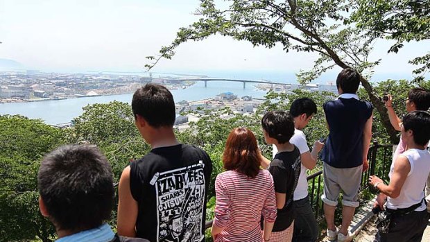 People watch the coastline from a hill following a tsunami warning in Ishinomaki.
