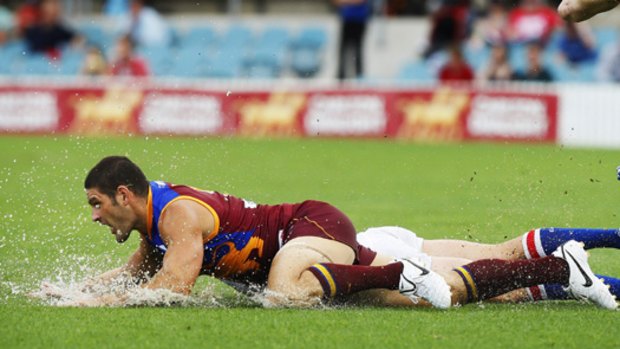 Brendan Fevola rides the slippery slide at Manuka Oval.