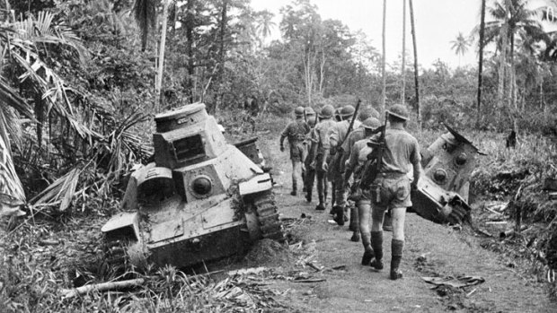 An Australian infantry section passes a Japanese Type 95 Ha-Go light tank, knocked out at Milne Bay, New Guinea in World War II. <i>Photo: Frank Bagnall, courtesy Australian War Memorial </i>