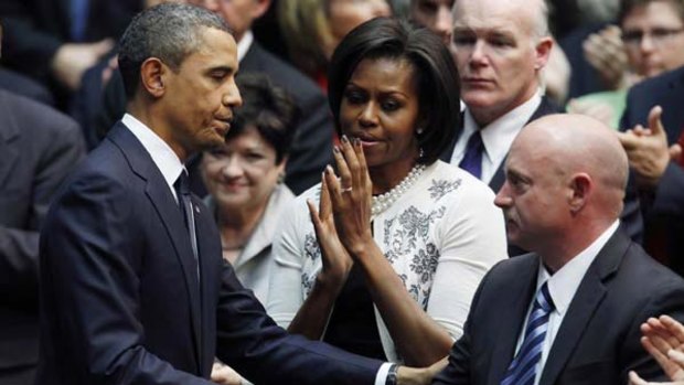 US. President Barack Obama shakes hands with Congresswoman Gabrielle Gifford's husband, NASA shuttle commander Mark Kelly, as first lady Michelle Obama looks on at the memorial for the Tucson shooting victims.