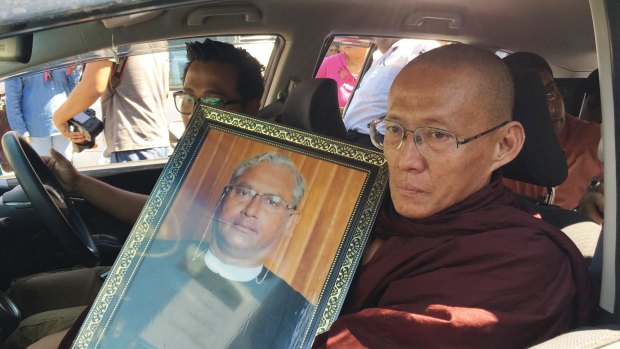 A Buddhist monk holds a portrait of Ko Ni on the way to his funeral.