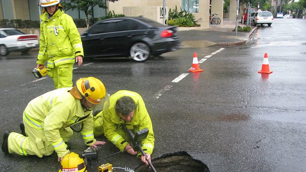 Firefighters test for gas in a sink hole that opened in a Fortitude Valley street this morning.