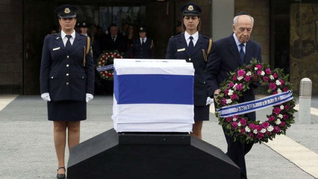 Israeli President Shimon Peres lays a wreath by the coffin of former prime minister Ariel Sharon at the Israeli Parliament in Jerusalem.