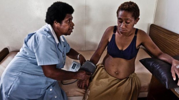 Baby worries: A nurse at the Port Moresby antenatal clinic examines a five-month-pregnant woman attacked by her husband who kicked her in the stomach and threw her out of the house.