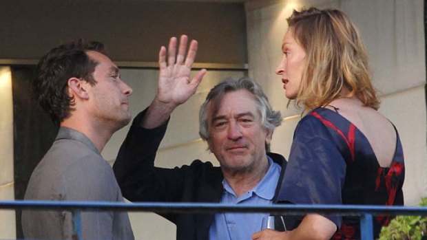 Cannes jury president Robert De Niro waves as he stands on a balcony next to jury members Jude Law and Uma Thurman.